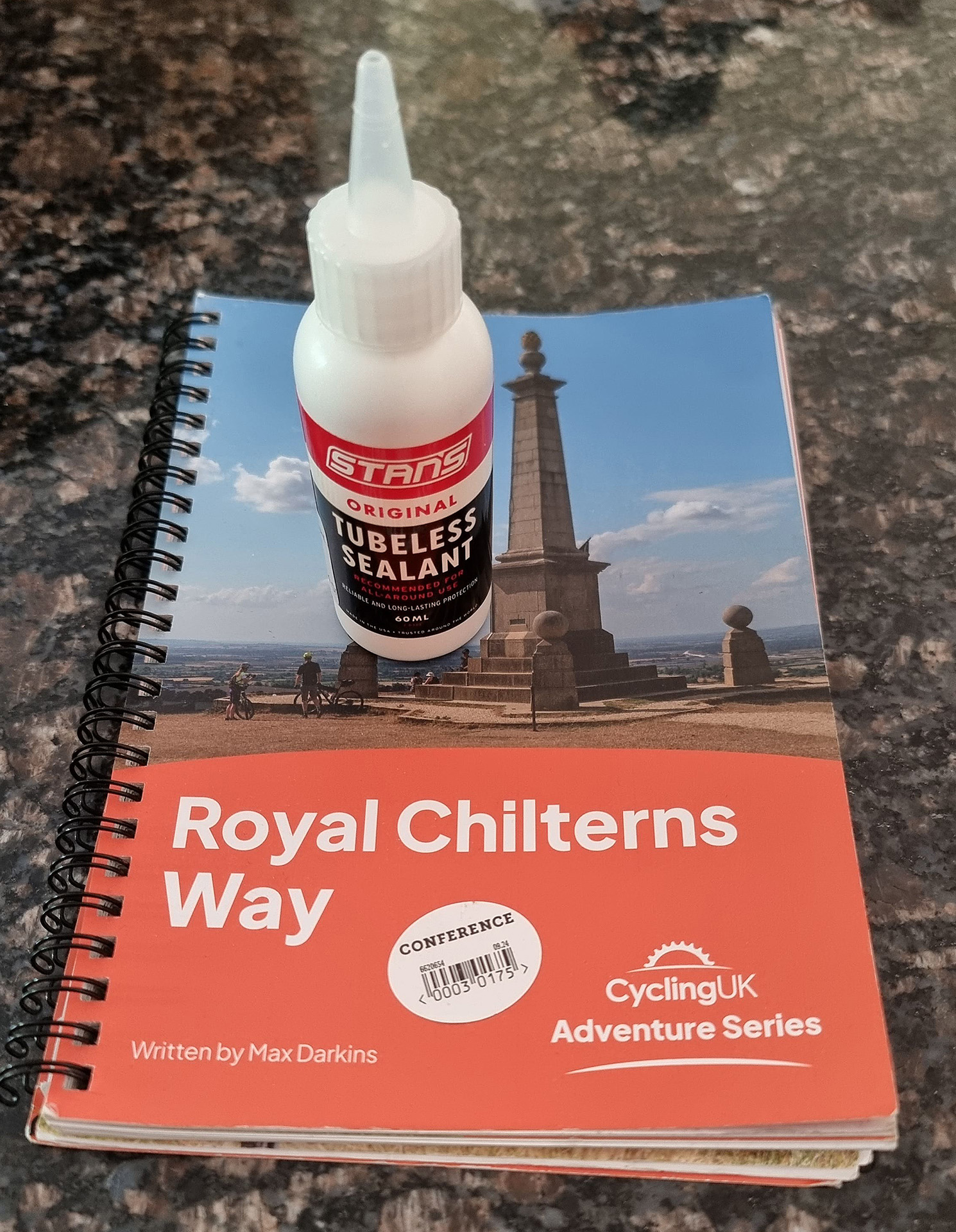 One of the small pots of Stan's tubeless tyre sealant I bought in Amersham, sitting on the excellent Cycling UK's Guidebook for the Royal Chilterns Way route